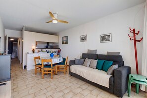 A compact living space with a kitchenette, a dining area, and a sofa with cushions. - Holiday Home “L'albatros Direct Beach Access 3” (Palavas-les-Flots)