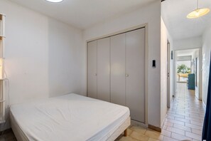 A bedroom with a bed, a wardrobe, and a door leading to a corridor.