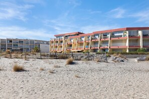 A multi-story hotel with balconies, a sandy beach in the foreground, and a clear sky. - Holiday Home “L'albatros Direct Beach Access 3” (Palavas-les-Flots)