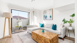 Een moderne woonkamer met een bank, salontafel en potplanten.