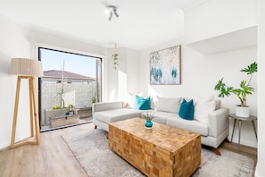 Ein modernes Wohnzimmer mit einer Couch, einem Couchtisch und Zimmerpflanzen.