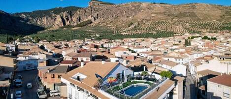 A hotel with a rooftop pool, surrounded by a town with terraced vineyards.