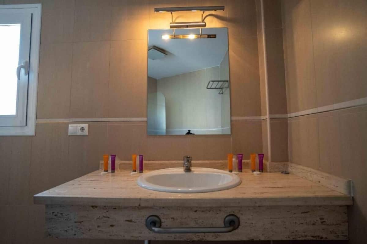 A bathroom with a sink, mirror, and toiletries.