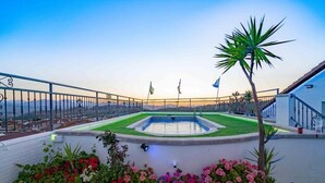 Ein Pool auf dem Dach mit einer Fontäne, umgeben von Blumenbeeten und einer Palme.
