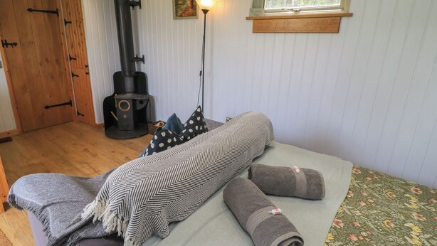 A cozy room with a bed, a fireplace, a window, and a door. - Bramleys (Watchet)