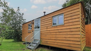A wooden cabin with a small porch, a window, and a door. - Bramleys (Watchet)
