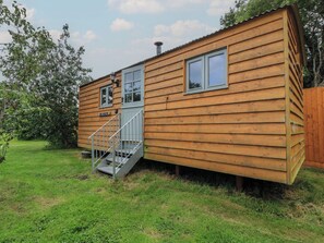 A wooden cabin with a small porch, a window, and a door. - Bramleys (Watchet)