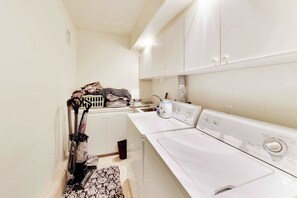 A laundry area with a washing machine, dryer, and stacked laundry.