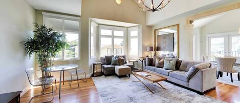 A spacious living room with a large window, a dining area, and a seating arrangement.