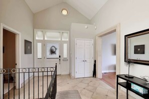 A hallway with a staircase, a white door, and a black console table with a decorative item.