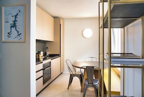 Een moderne keuken met roestvrijstalen apparatuur, een eettafel met stoelen en een kaart aan de muur.
