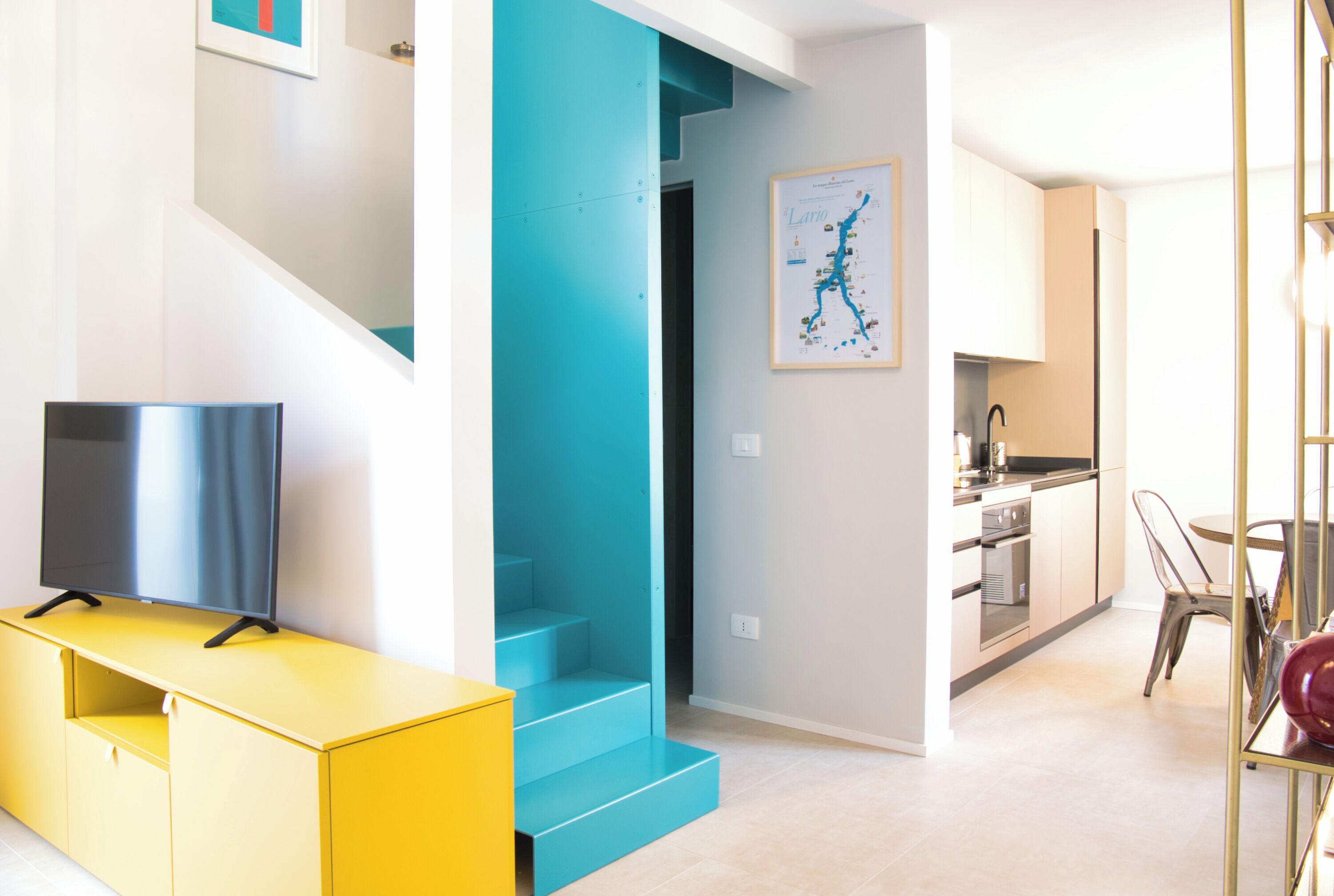 Un apartament modern amb escala, cuina i zona de dinar.
