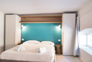 Une chambre d’hôtel moderne avec un lit, un mur d’accent de couleur turquoise et une fenêtre avec des rideaux.