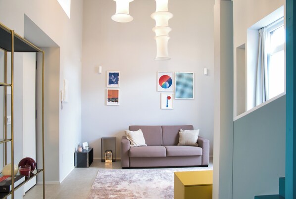 Un salon moderne avec un canapé, des œuvres d’art au mur et des luminaires suspendus.