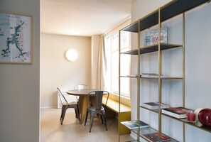 Un coin repas avec une table et des chaises, une bibliothèque et une carte accrochée au mur.