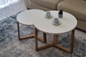 Two round tables with saucers and cups, a small potted plant, and a beige sofa in a room with a patterned rug. - Bright Nest Bande Nere – Milano Apartment (Milano)