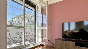 A room with a large window, a flat-screen TV, and a wooden cabinet.