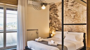 A modern hotel room with a large bed, a view through a sliding door, and a unique wall-mounted light fixture.