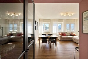 A spacious living area with a dining table, multiple sofas, and large windows with curtains. - Nest78 - Skyline Lake view in the heart of Lecco (Lecco)