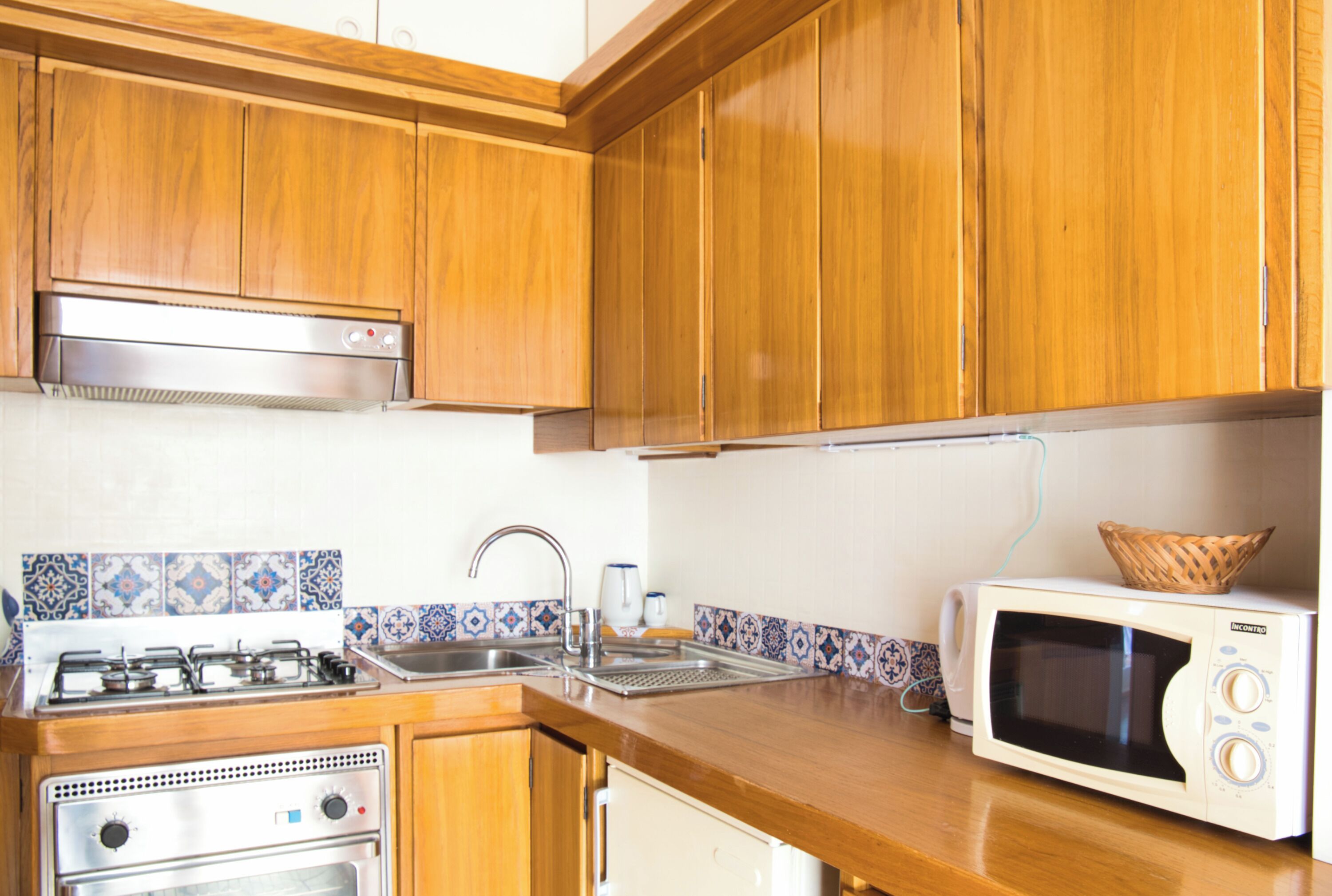 A kitchen with wooden cabinets, a gas stove, a microwave, and a sink.