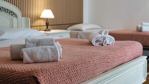 Habitación de hotel con cama, almohadas, lámpara y toallas dobladas con esmero.