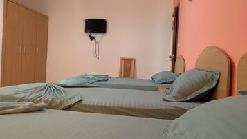 Une chambre avec deux lits, une armoire, une télévision et un miroir.