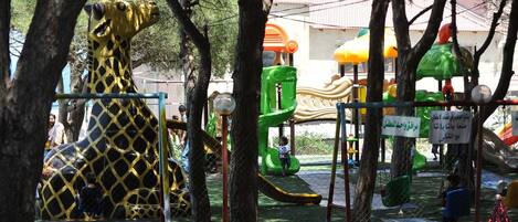 A playground with various play structures, including a giraffe-shaped climbing frame and a slide.