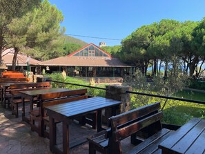 Outdoor wooden tables and benches, a building with a red roof, and a body of water. - Montazah Residence (Bizerte)
