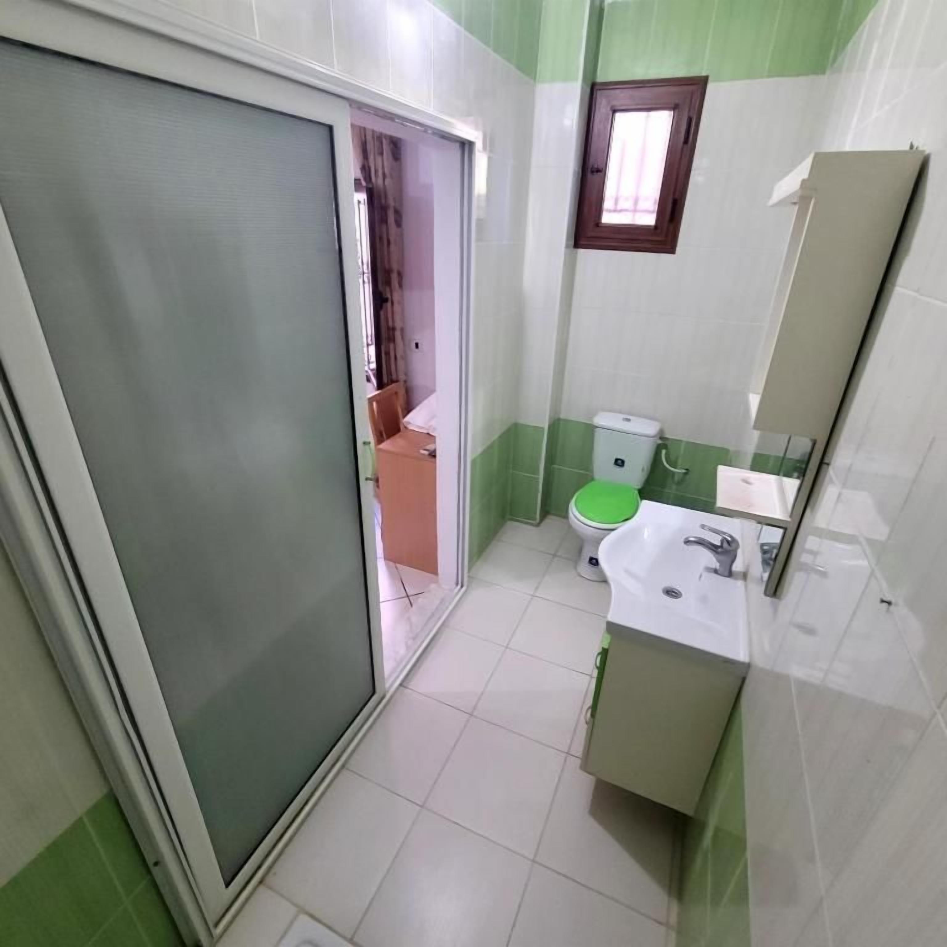 A bathroom with a toilet, sink, and a mirror.