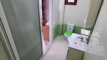 A bathroom with a toilet, sink, and a mirror.