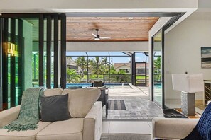 Ein modernes Wohnzimmer mit einer Couch, einem Couchtisch und Blick auf einen Swimmingpool.