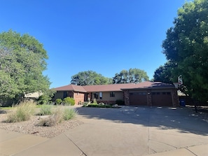 A single-story house with a garage, a driveway, and a basketball court. - Spacious, Big Family-Friendly 4 Bedroom Ranch Home in Hays, Kansas (Hays)