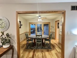 A dining area with a wooden table, chairs, a clock, and a ceiling fan. - Spacious, Big Family-Friendly 4 Bedroom Ranch Home in Hays, Kansas (Hays)