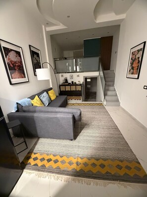 A modern living room with a grey sofa, patterned rug, and framed artwork on the walls. - ENTIRE APARTMENT IN DOWNTOWN NAPLES (Napoli)