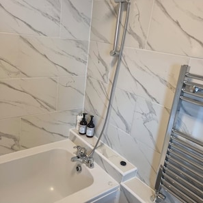 Ein Badezimmer mit Badewanne, Dusche und Handtuchhalter.