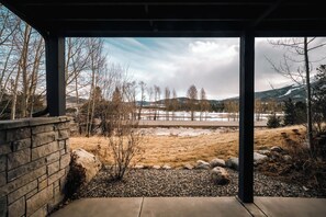 Un espace extérieur abrité offrant une vue sur un paysage naturel comprenant des arbres, un champ et des collines lointaines.