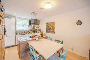 A modern kitchen with a dining area, wooden cabinets, a microwave, and a large window. - Ground Floor of a Villa in Toulon - Private Pool (Toulon)