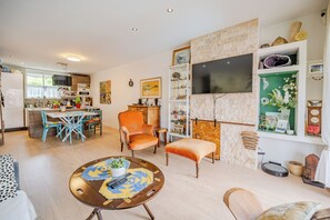 A modern living room with a round coffee table, a sofa, and a dining area with chairs. - Ground Floor of a Villa in Toulon - Private Pool (Toulon)