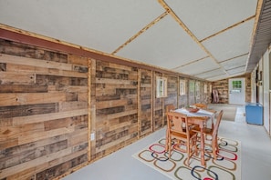 Ein Zimmer mit Holzwandverkleidung, einem Esstisch mit Stühlen und einer Decke mit freiliegenden Balken.