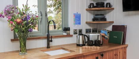 Una cocina con encimera de madera, un lavamanos, una ventana y un cartel de seguridad contra incendios en la pared.