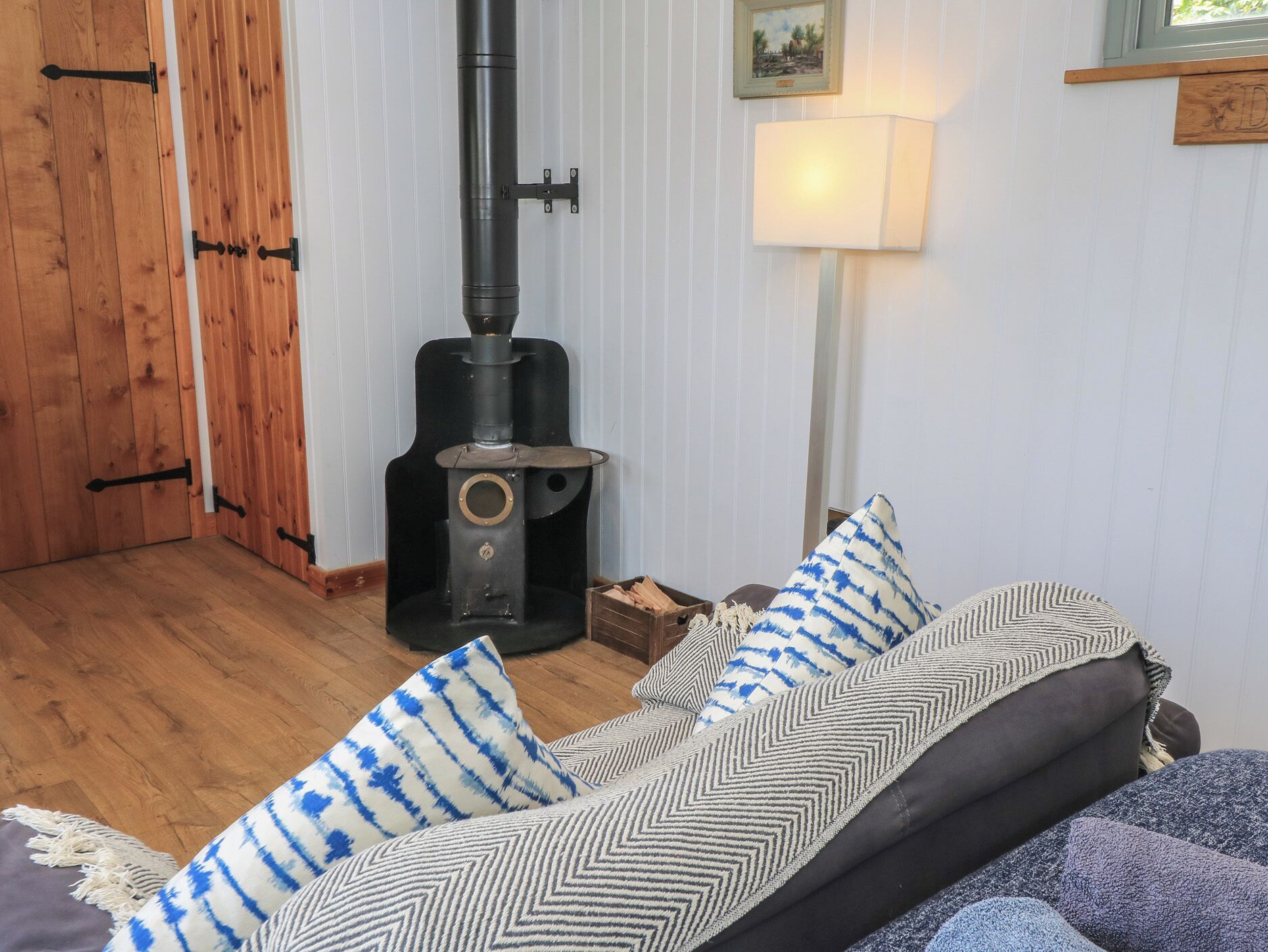 Una habitación acogedora con una estufa de leña, un sofá con cojines estampados y una puerta de madera.