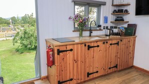 A wooden kitchen with a window, a fire extinguisher, and a view of the outdoors. - Damsons (Taunton)