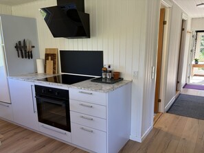 Eine moderne Küche mit Einbauofen, Flachbildfernseher und einer Arbeitsplatte mit Spüle.