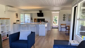 Una cocina moderna con armarios blancos, una isla central y una zona de comedor con sillas azules.