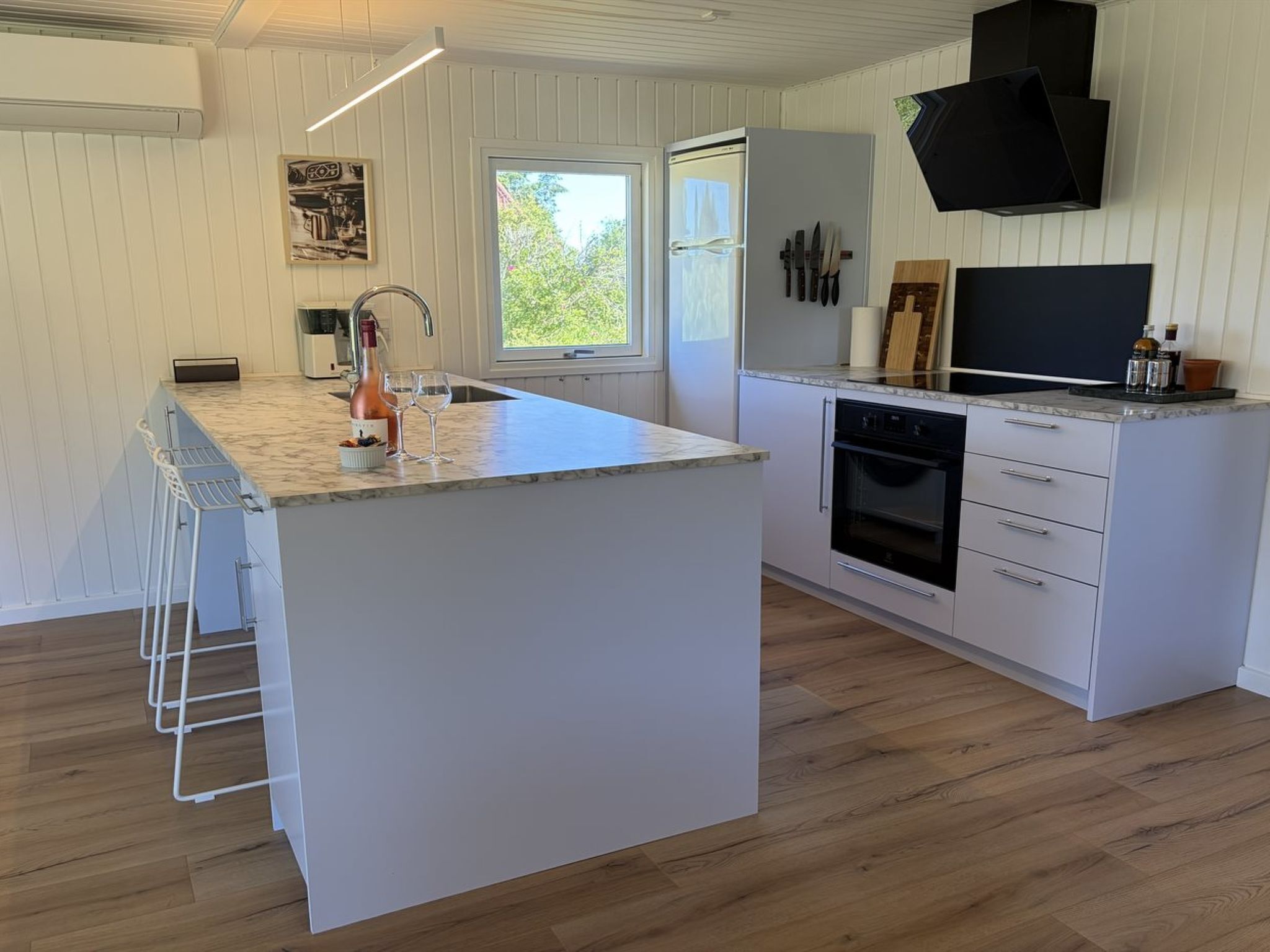 A modern kitchen with a central island, a built-in oven, and a large window.