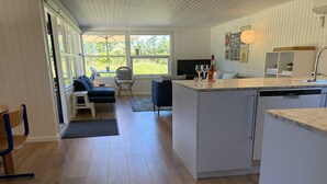 Una cocina moderna con lavavajillas integrado, un comedor con mesa y sillas, y una zona de estar acogedora con sofá y sillones.