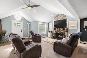 A cozy living room with a stone fireplace, ceiling fan, and two reclining chairs. - Walloon Waypoint - Walloon Lake (Bear Creek Township)
