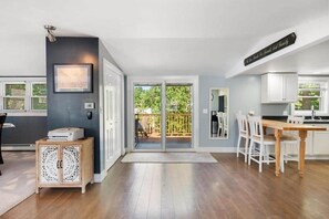 A modern kitchen with white cabinets, a wooden dining table, and a sliding glass door leading to a balcony. - Walloon Waypoint - Walloon Lake (Bear Creek Township)
