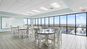 A conference room with a large table and chairs, large windows with a view of the landscape, and an exit sign on the ceiling. - Phoenix 6 1111 (Orange Beach)