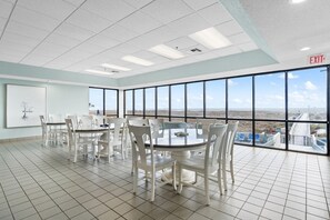 A conference room with a large table and chairs, large windows with a view of the landscape, and an exit sign on the ceiling. - Phoenix 6 1111 (Orange Beach)